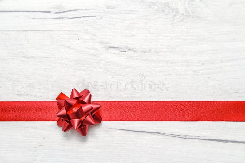 Dekoratives rotes Band und Bogen auf einem Hintergrund von weiß gestrichenen rustikalen Boards mit Copyspace stockfotografie Dekoratives rotes Band und Bogen auf einem Hintergrund von weiß gestrichenen rustikalen Boards mit Copyspace stockfotografie
