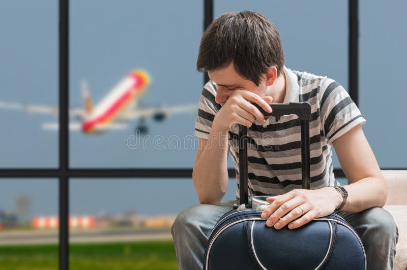 Delayed aeroplane concept. Tired passenger is sitting with baggage in airport.