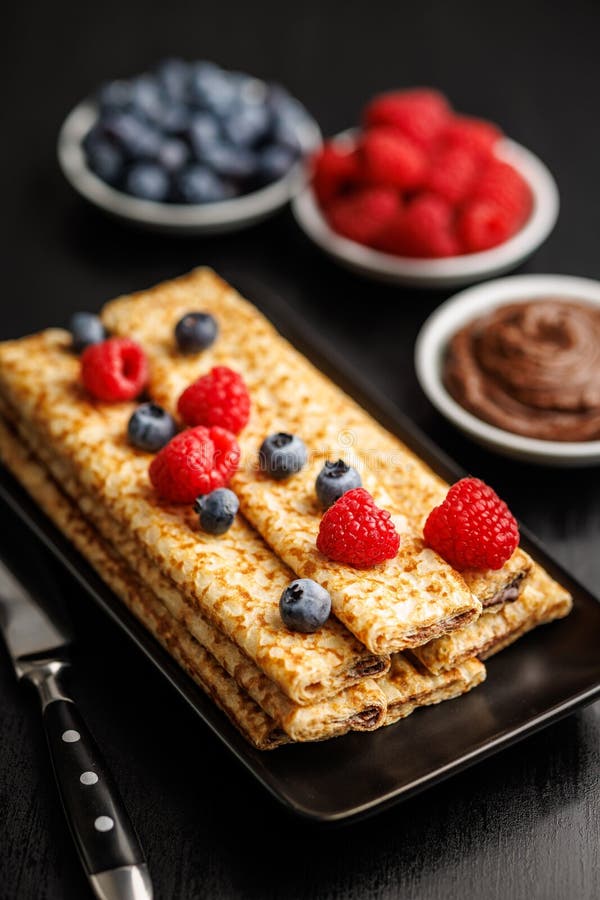 Delicate crepes stacked with blueberries and raspberries, served with a chocolate spread