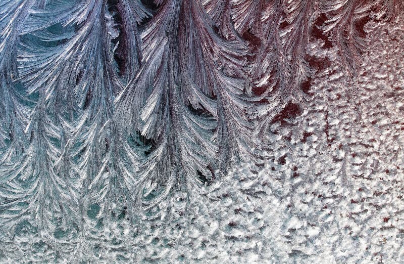 Delicate patterns of frost crystals on a sparkling glass stock photography