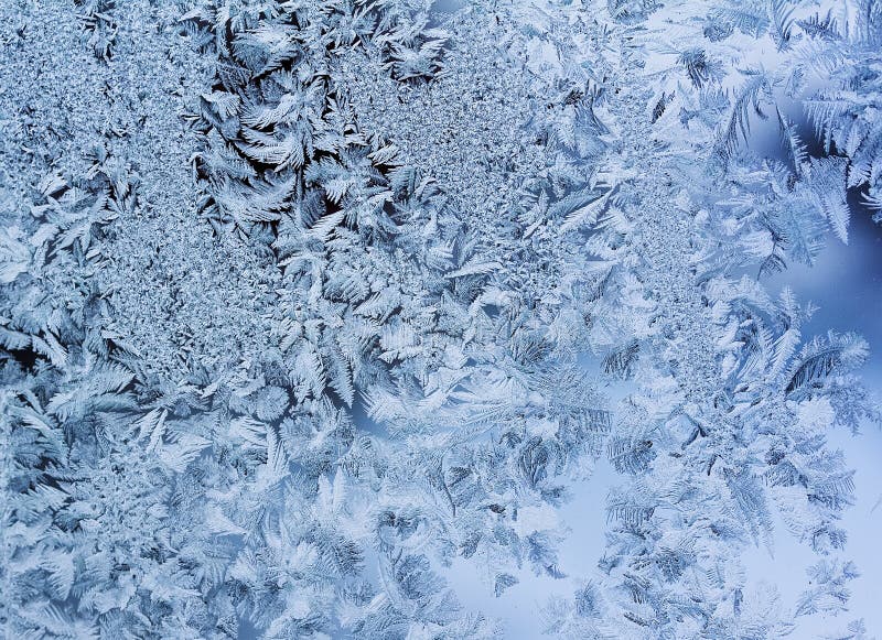 Delicate patterns of frost crystals on a sparkling glass stock photo