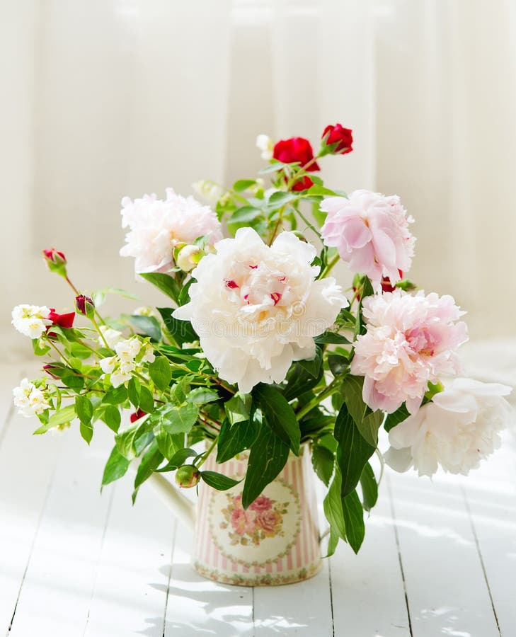 Delicate peonies in a water can