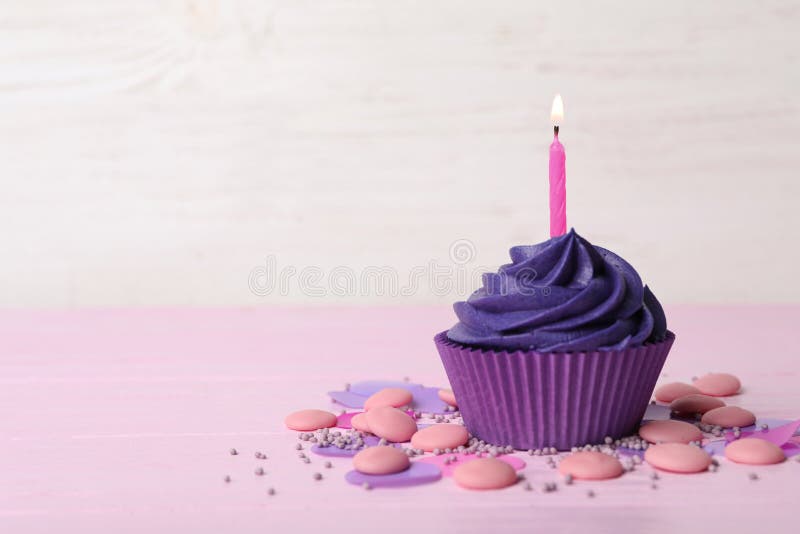 Delicious birthday cupcake with cream and burning candle on pink table. Space for text. Delicious birthday cupcake with cream and burning candle on pink table. Space for text