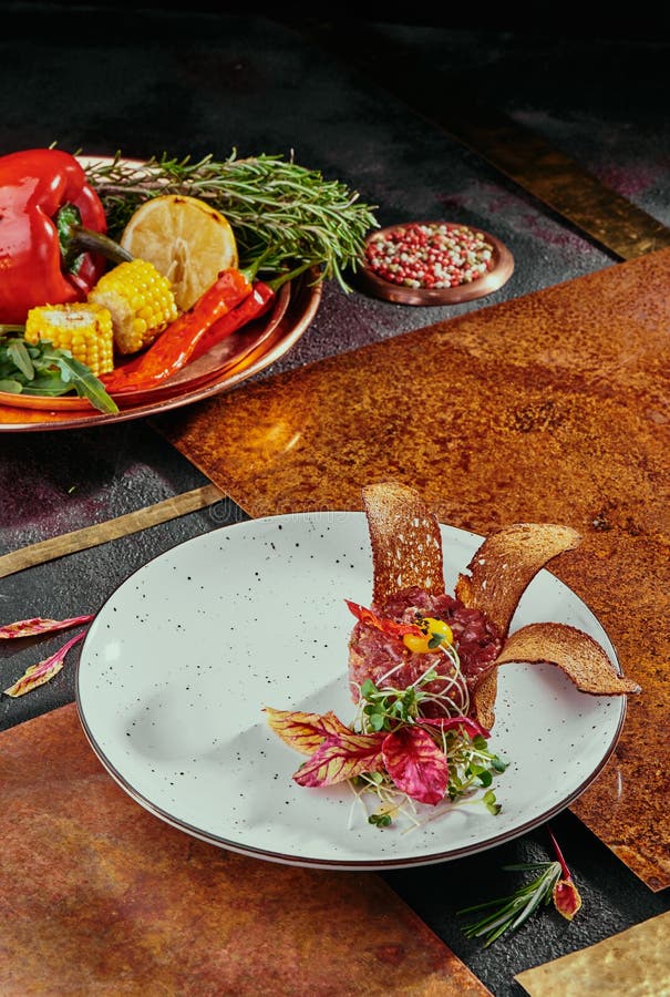Delicioso tartar de carne con pan tostado y ensalada sobre un plato blanco sobre fondo de cobre. comida saludable hecha de fotos de archivo