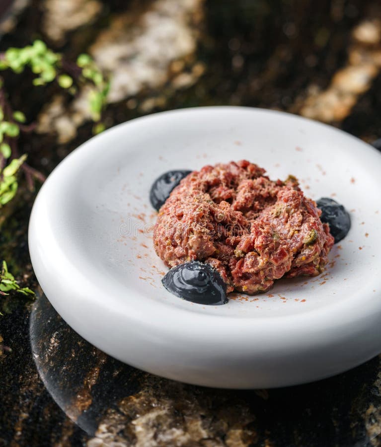 Delicioso tartar de carne de ternera con pepino en picante y salsa de trufa en la mesa de mármol con copas de vino. alimento salud foto de archivo