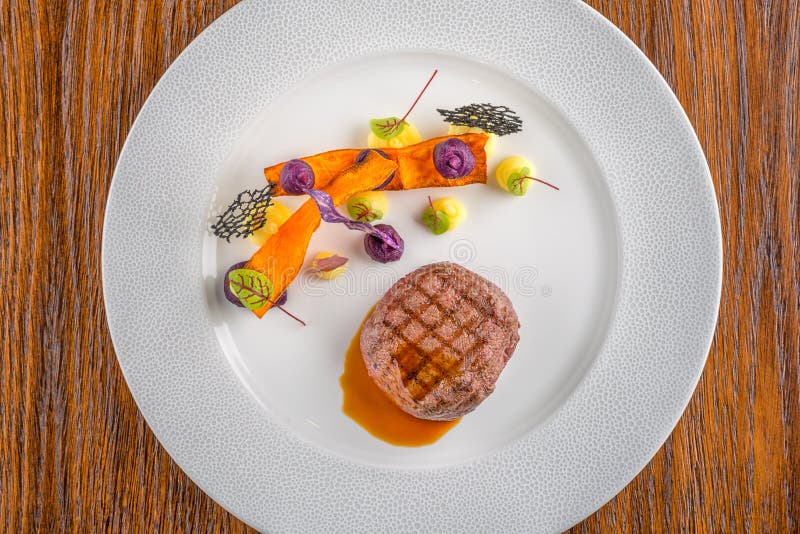 Delicious beef steak with sauce and vegetable, served on white plate, modern gastronomy, michelin restaurant