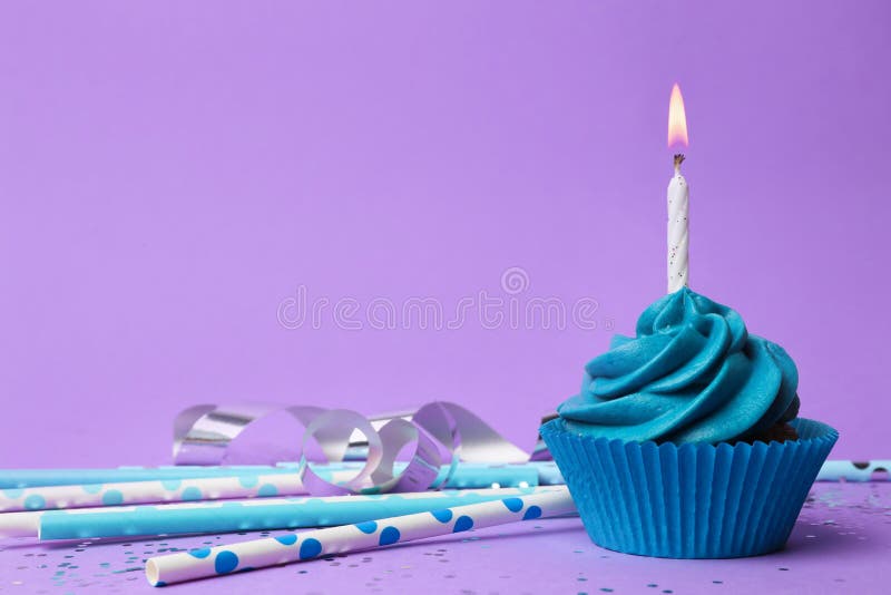 Delicious birthday cupcake with blue cream and burning candle on violet background. Space for text royalty free stock photos Delicious birthday cupcake with blue cream and burning candle on violet background. Space for text royalty free stock photos