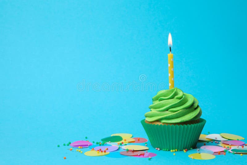Delicious birthday cupcake with green cream and candle on light blue background. Space for text royalty free stock photo Delicious birthday cupcake with green cream and candle on light blue background. Space for text royalty free stock photo
