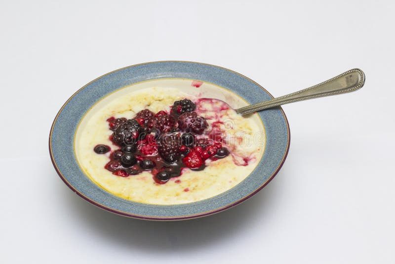 A delicious bowl of hot porridge with a forest fruit selection and a honey drizzle