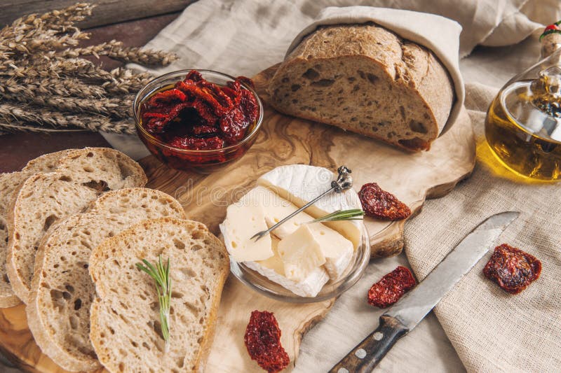 Delicious brie cheese Camembert with sun-dried tomatoes with olive oil and homemade bread. Traditional quick snack for home royalty free stock image Delicious brie cheese Camembert with sun-dried tomatoes with olive oil and homemade bread. Traditional quick snack for home royalty free stock image