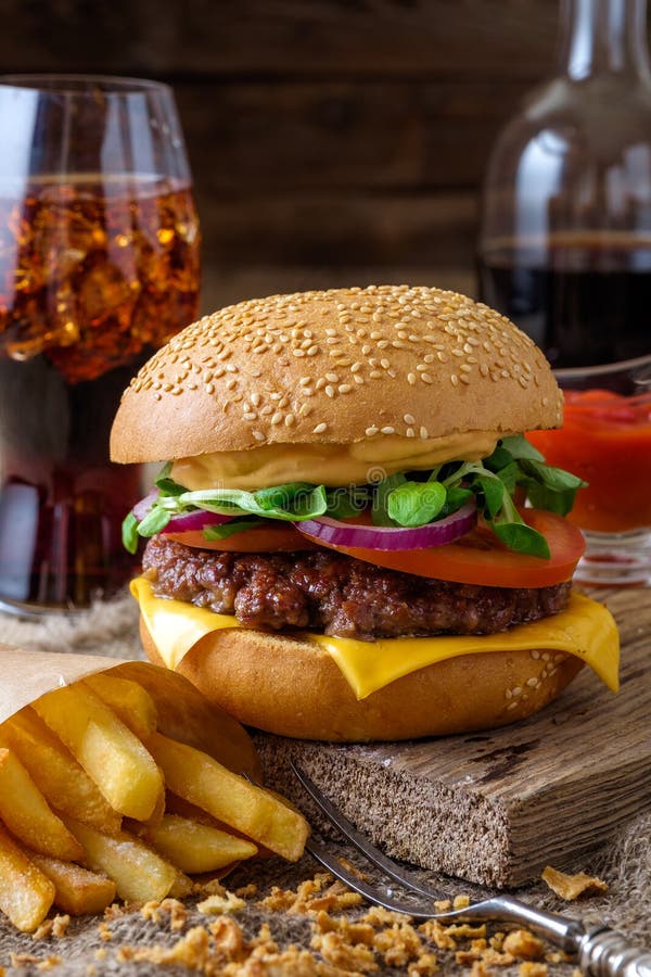Delicious Burger with Chips and Soda on Wooden Table. Stock Photo