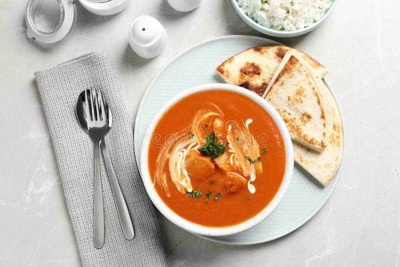 Delicious butter chicken served on grey table, top view