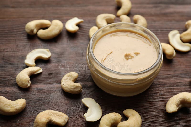 Delicious cashew butter and ingredient on wooden table, closeup