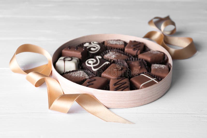 Delicious chocolate candies in box on wooden table