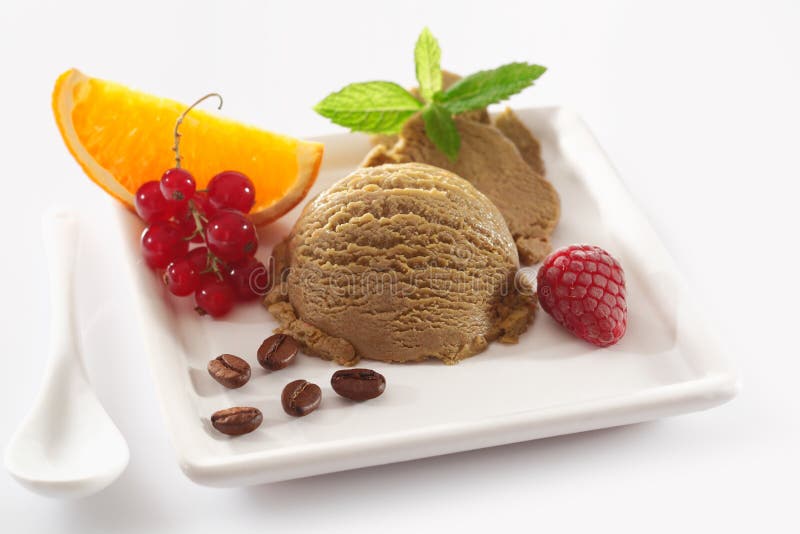 Delicious coffee ice-cream dessert served on a white platter garnished with colourful tropical fruit and coffee beans