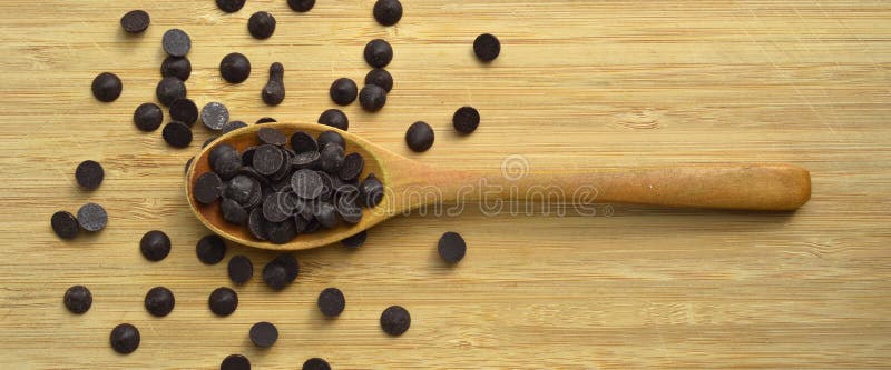 Delicious dark chocolate drops in wooden spoon