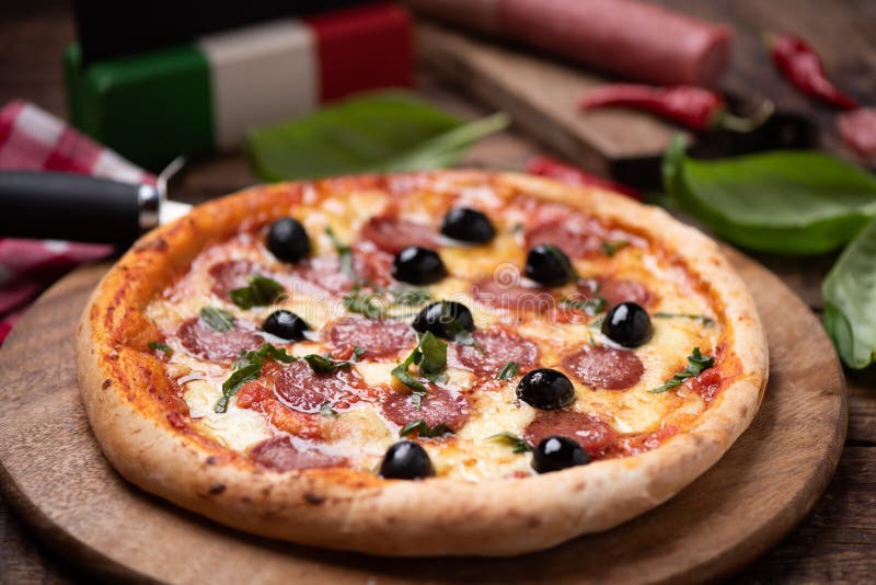 Delicious fresh oven baked spicy salami or pepperoni pizza with melted cheese and olives on a wooden board royalty free stock photos Delicious fresh oven baked spicy salami or pepperoni pizza with melted cheese and olives on a wooden board royalty free stock photos