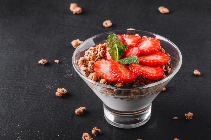 Delicious granola with yogurt and fresh strawberry in glass on black background. royalty free stock photos Delicious granola with yogurt and fresh strawberry in glass on black background. royalty free stock photos