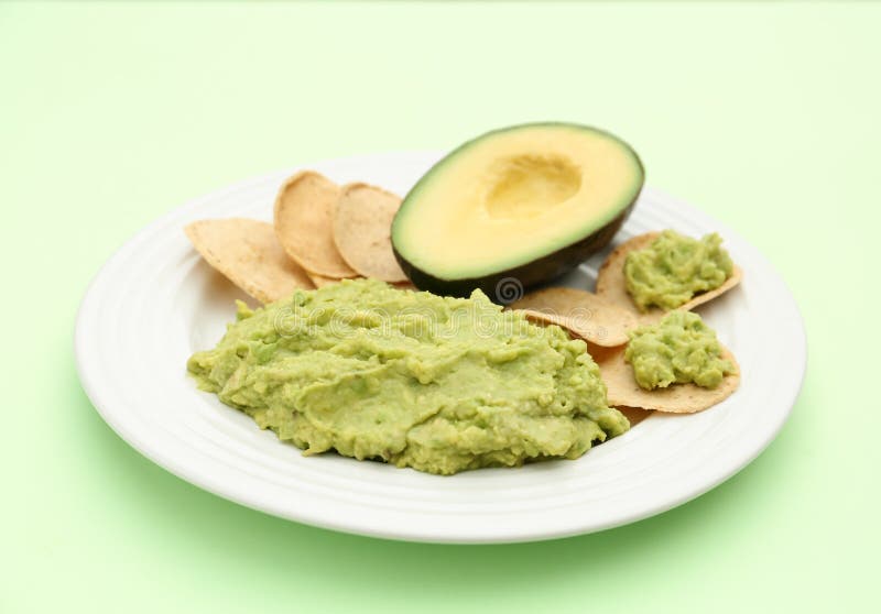 Delicious guacamole, avocado and chips on light green background royalty free stock photo