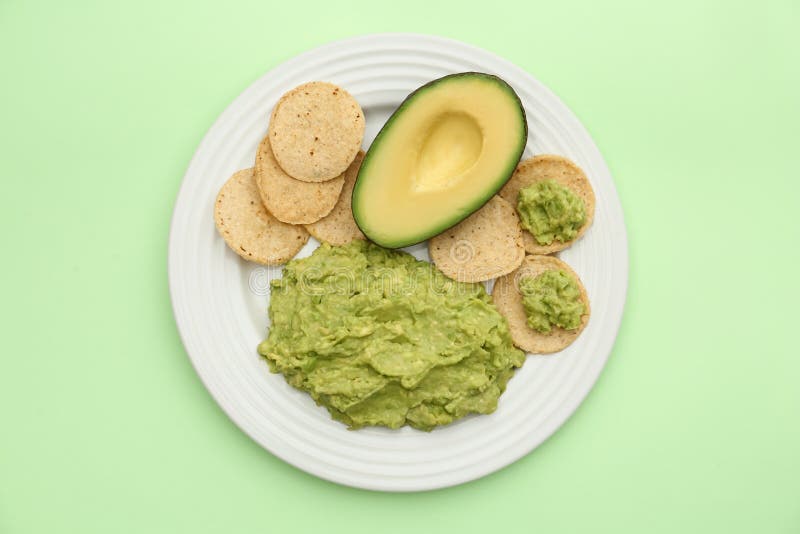 Delicious guacamole, avocado and chips on light green background, top view stock images