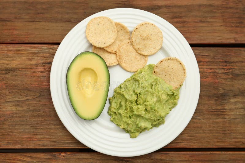 Delicious guacamole, avocado and chips on wooden table, top view royalty free stock image