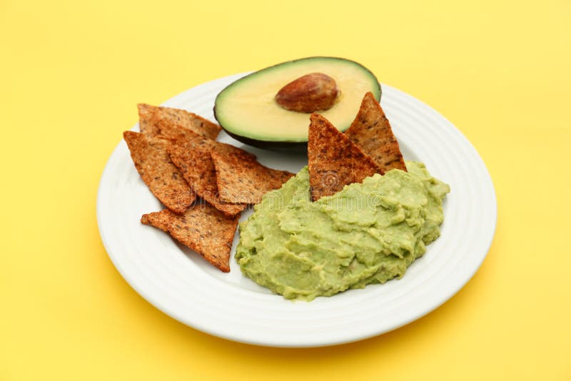 Delicious guacamole, avocado and nachos on yellow background stock photo