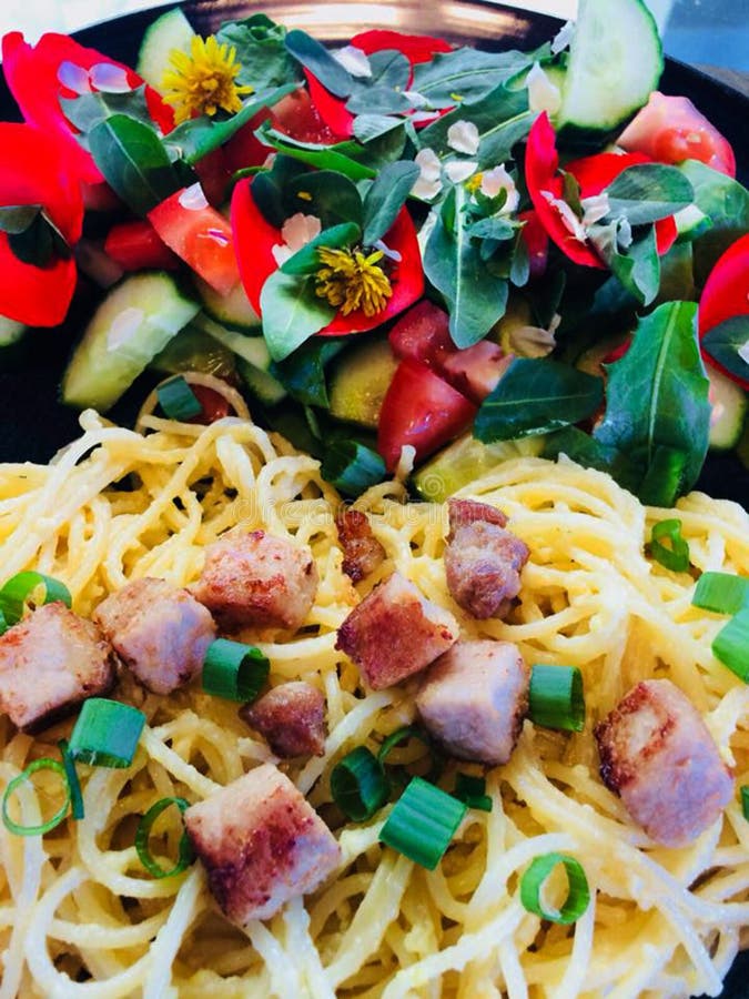 Delicious home cooked pasta chicken and fresh garden salad with flower petals and natures greens