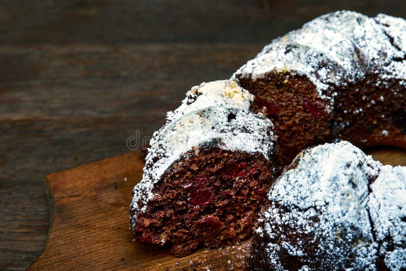 Chocolate cake with sour cherries and wallnuts on a wooden cutting board over rustic vintage background, selective focus