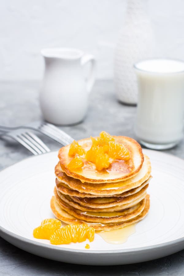Delicious homemade pancakes with tangerines and honey, glass of milk on a plate royalty free stock photography Delicious homemade pancakes with tangerines and honey, glass of milk on a plate royalty free stock photography