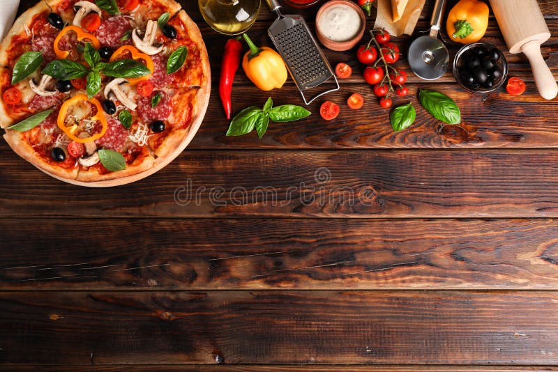 Delicious pizza and ingredients on wooden background