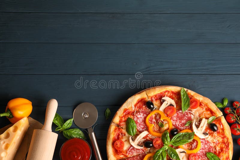 Delicious pizza and ingredients on wooden background