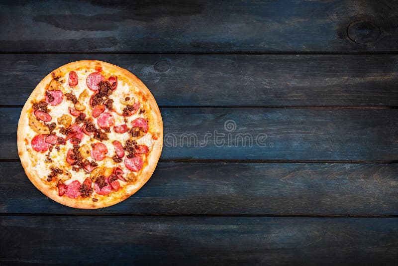 Delicious pizza meat mix with smoked sausage, chicken, minced meat, and pepperoni on a dark wooden background. Top view stock image Delicious pizza meat mix with smoked sausage, chicken, minced meat, and pepperoni on a dark wooden background. Top view stock image