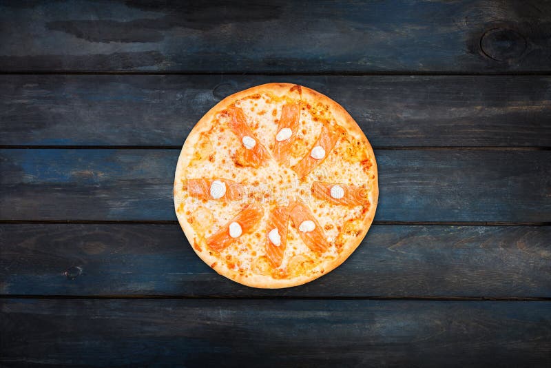 Delicious pizza with salmon and Philadelphia cheese on a dark wooden background. Top view center orientation stock images Delicious pizza with salmon and Philadelphia cheese on a dark wooden background. Top view center orientation stock images