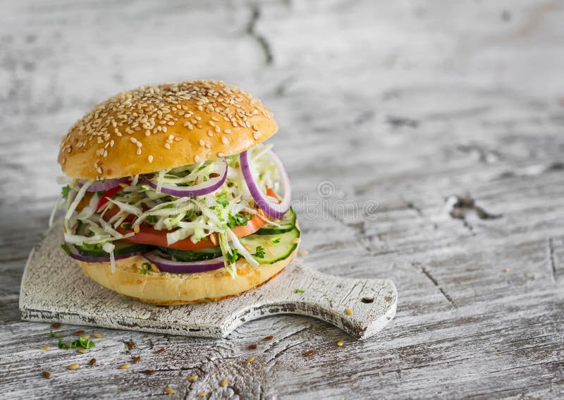 Delicious veggie burger with cabbage, tomato, cucumber, onions and peppers on a light wooden surface royalty free stock images Delicious veggie burger with cabbage, tomato, cucumber, onions and peppers on a light wooden surface royalty free stock images