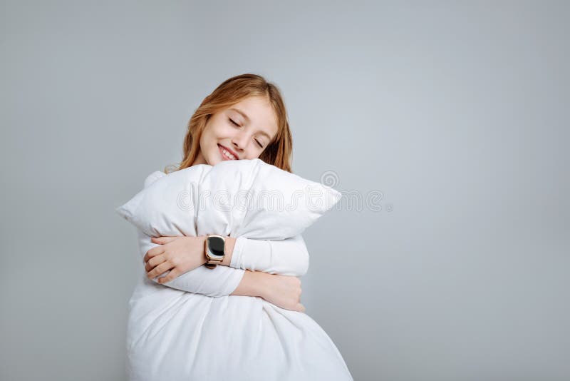 Delighted cute little girl embracing pillow