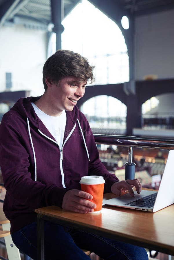 Delightful man printing in laptop over paper cup of coffee