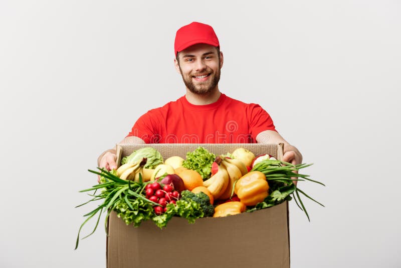 Delivery Concept - Handsome Cacasian delivery man carrying package box of grocery food and drink from store. Isolated on royalty free stock photo Delivery Concept - Handsome Cacasian delivery man carrying package box of grocery food and drink from store. Isolated on royalty free stock photo