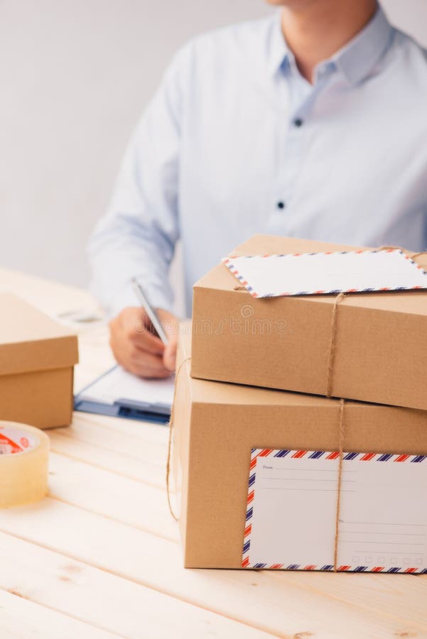 Delivery concept. Man signs papers among parcels stock image