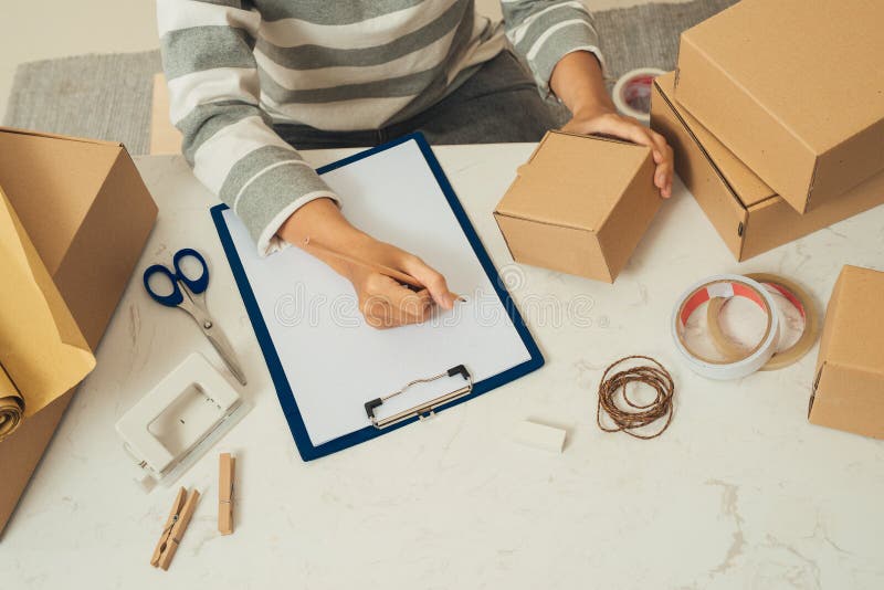 Delivery concept. Woman signs papers among parcels, close up royalty free stock photo