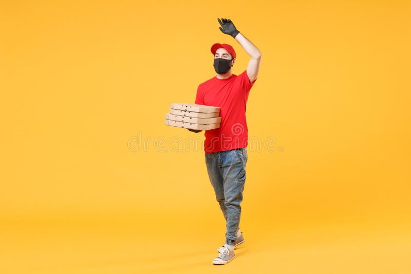 Delivery man in gloves and mask holds box on yellow background