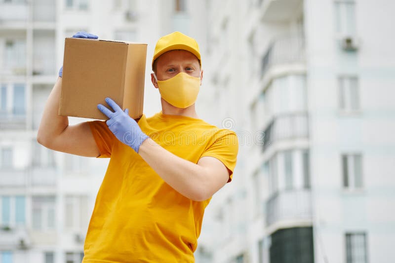 Delivery Man in Yellow Uniform Medical Face Mask and Gloves Holds