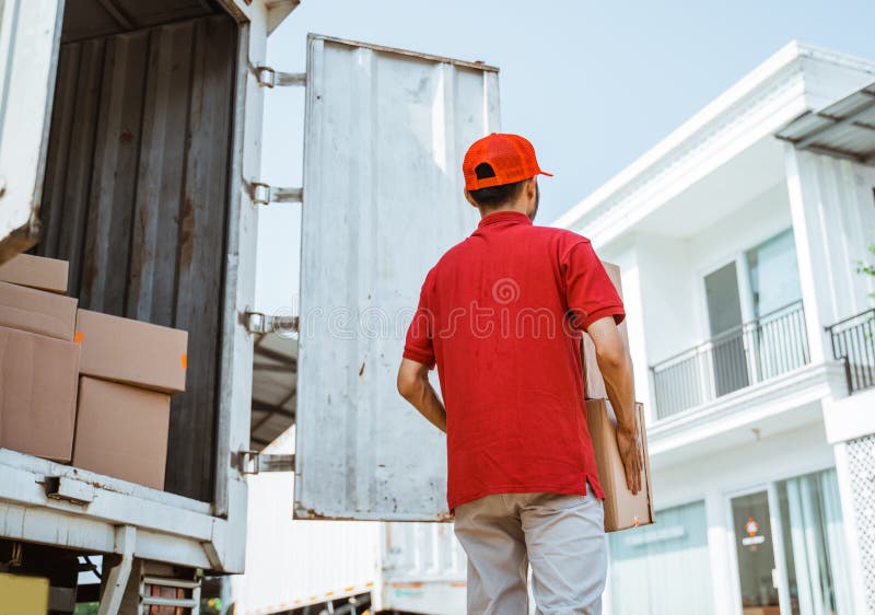 Delivery Man in Red Delivers Boxes To Customers from Containers Stock