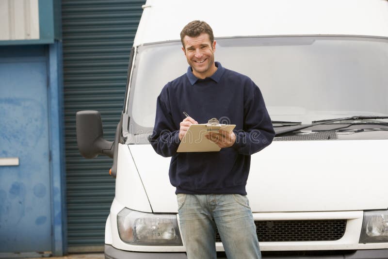 Delivery person standing with van writing stock image Delivery person standing with van writing stock image