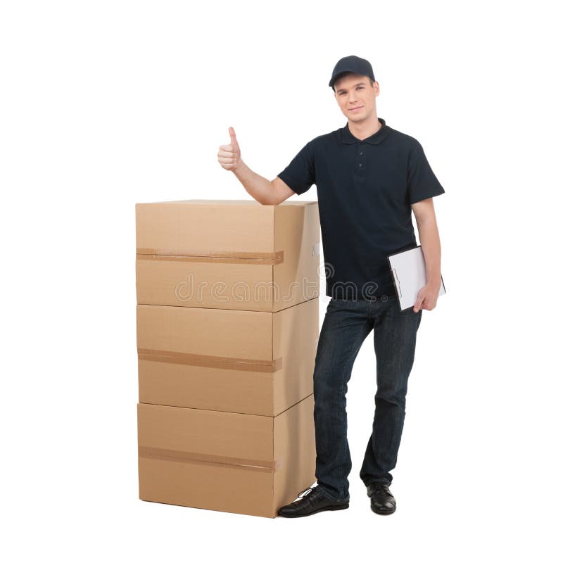 Deliveryman. Cheerful young deliveryman standing near the stack stock photos