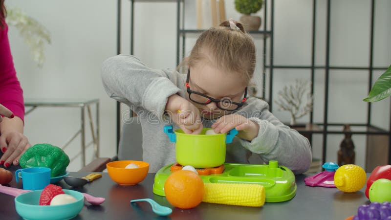 Deliziosa ragazza della sindrome di Down che sta imparando a cucinare con i giocattoli della cucina video d archivio