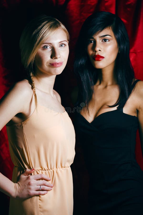 Della donna amici castana e biondi insieme su fondo rosso, raggiro fotografie stock Della donna amici castana e biondi insieme su fondo rosso, raggiro fotografie stock