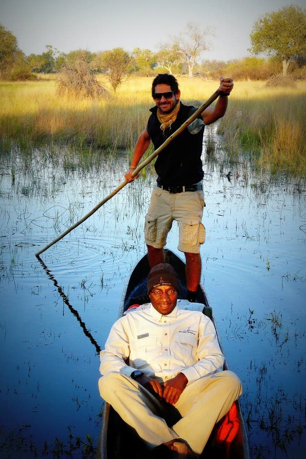 Delta di Okavango, Botswana - 14 luglio di 2012: Le guide locali ed i turisti guidano le barche tradizionali chiamate mokoros che fotografia stock Delta di Okavango, Botswana - 14 luglio di 2012: Le guide locali ed i turisti guidano le barche tradizionali chiamate mokoros che fotografia stock