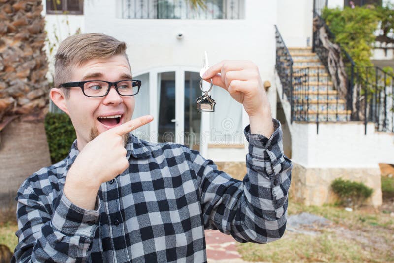 Demeure, maison de achat, immobiliers et concept de propriété - homme bel montrant sa clé à la nouvelle maison photographie stock Demeure, maison de achat, immobiliers et concept de propriété - homme bel montrant sa clé à la nouvelle maison photographie stock