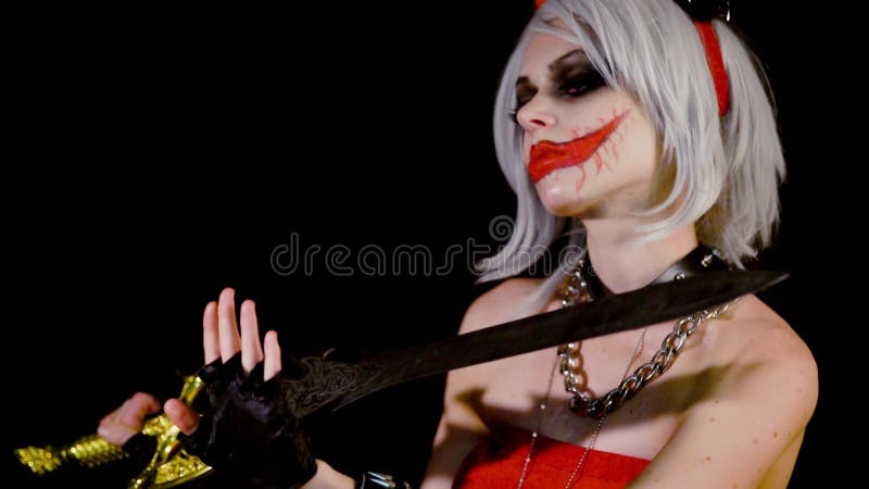 Demon zombie girl with horns preparing for halloween, celebrate. Sexual female satan woman devil makes a manicure, cuts