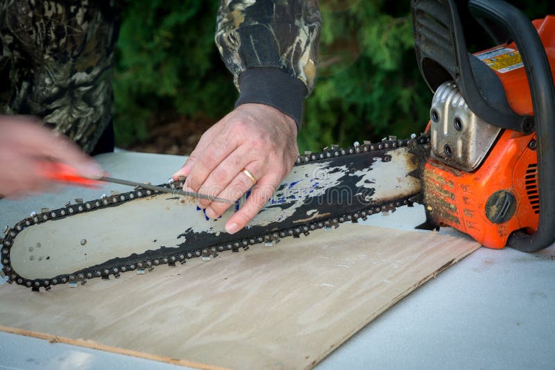 Man sharpens the bar on a chainsaw with a file. Demonstrating chainsaw sharpening with a small file